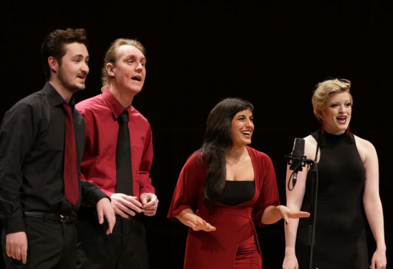 Stage photo of Michelle Kelly on stage singing into a microphone as part of a quartet