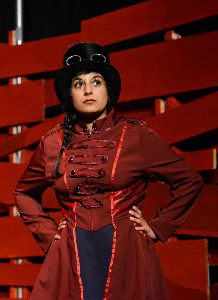 Promotional shot of Michelle Kelly posing in a circus ringleader-style coat and top hat