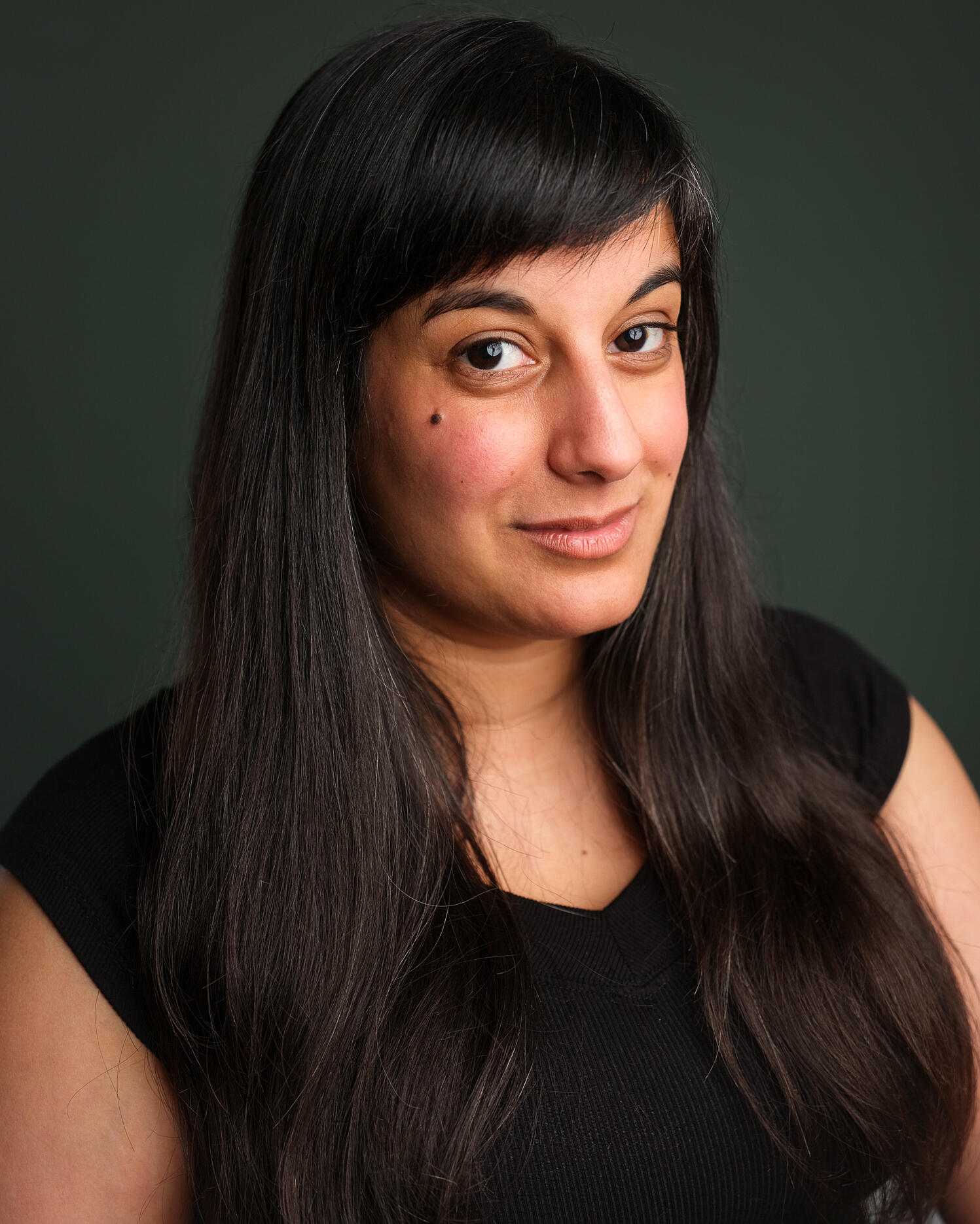 Stage photo of Michelle Kelly as a secretary, perched on a box and holding a clipboard