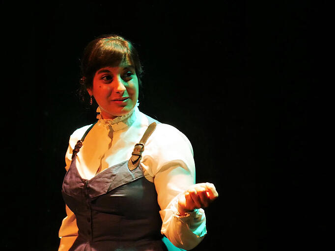 Michelle Kelly in period dress gestures to someone out of shot