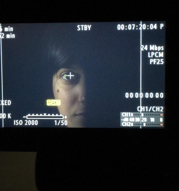 Behind the scenes photo of close-up of Michelle Kelly through camera viewfinder