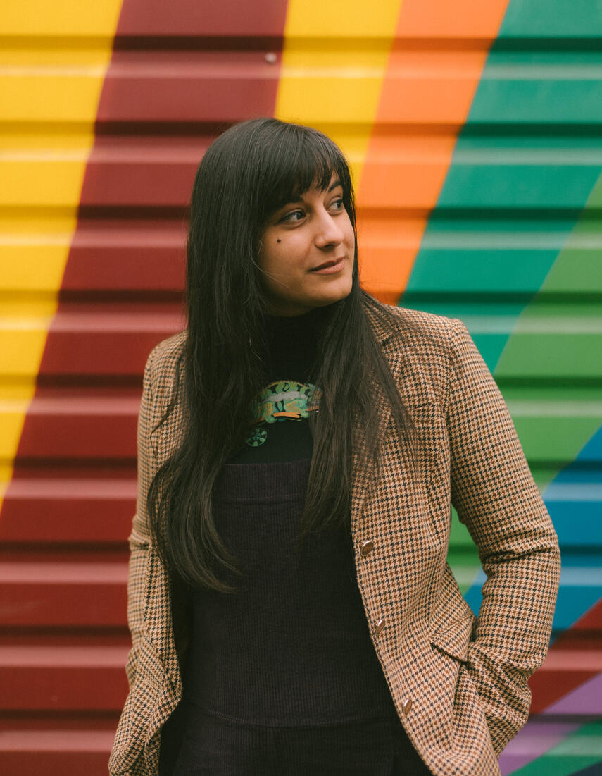 Stage photo of Michelle Kelly as a secretary, perched on a box and holding a clipboard