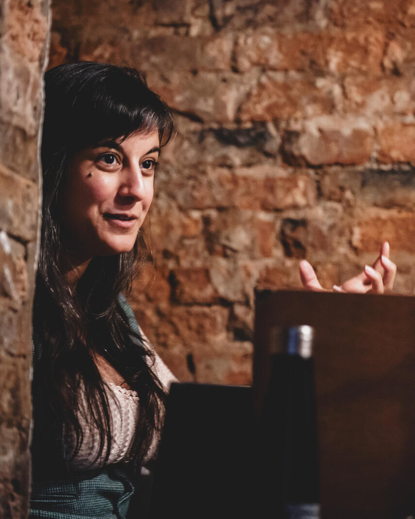 Photo of Michelle sitting behind a GM screen and gesturing dramatically with one hand